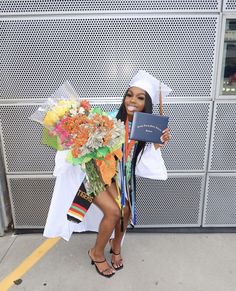 a woman in a graduation gown holding a bouquet of flowers