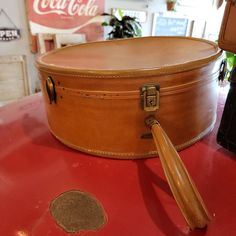 an old fashioned suitcase sitting on top of a red table next to a coca cola sign