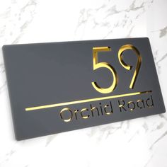 a sign that reads 599 orchid road on the side of a marble wall with gold lettering