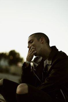 a man sitting on the ground with his hand to his face