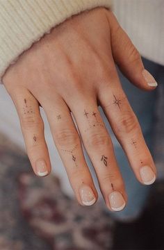 a woman's hand with tattoos on it and a cross tattoo on the middle finger