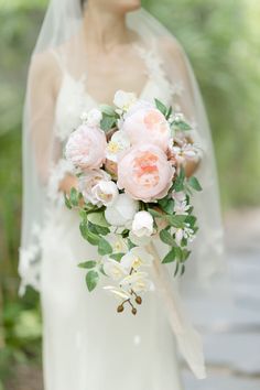 a bride holding a bouquet of pink and white flowers