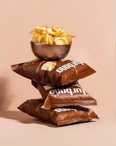 three bags of chips stacked on top of each other in front of a pink wall