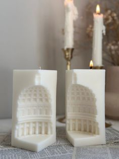 two white candles sitting on top of a table