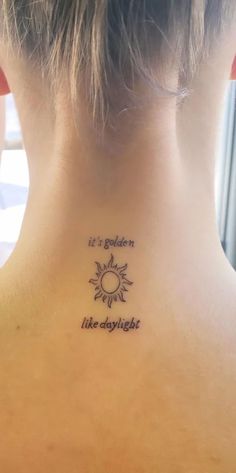 the back of a woman's neck with a tattoo saying it is golden like daylight