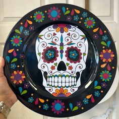 a person holding up a plate with a skull painted on it