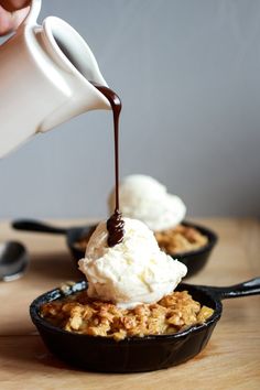 someone pouring ice cream on top of a skillet filled with dessert crumbs