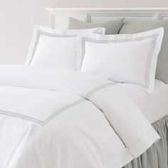 a bed with white and blue sheets and pillows