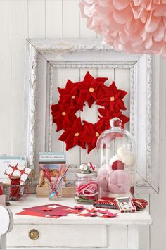 a white table topped with lots of items and a red wreath on top of it