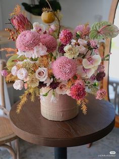 a vase filled with flowers sitting on top of a wooden table next to a chair