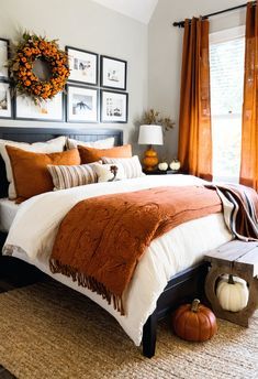 a bedroom decorated for fall with pumpkins on the floor and pictures above the bed