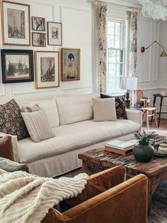 a living room filled with lots of furniture and pictures on the wall above it's windows