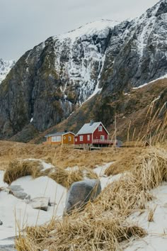 a red house sitting on top of a snow covered hill next to a tall mountain