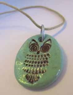 an owl shaped ceramic pendant on a cord