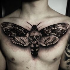 a man's chest with a skull and butterfly tattoo on his chest, in black and white