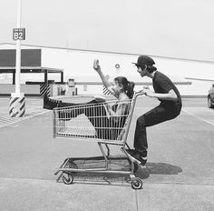 a man pushing a woman in a shopping cart