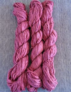 three skeins of pink yarn on a blue surface