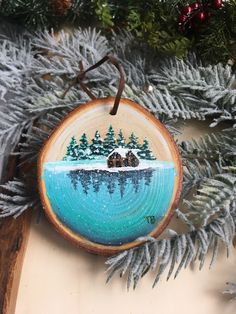 a christmas ornament hanging from a tree with snow and trees in the background