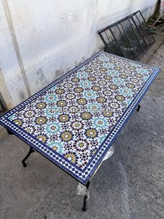 a table that is sitting outside on the ground next to a wall with a fence in front of it