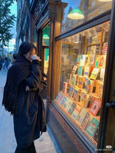 a woman walking down the street in front of a book store looking at her phone