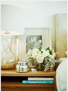 a vase with white flowers sitting on top of a wooden table next to a lamp