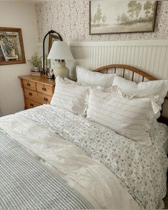 a bed with white and blue comforters in a bedroom next to a lamp on a dresser