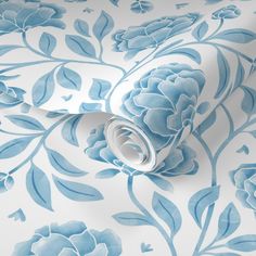 a blue and white wallpaper with large flowers on it's side, next to a roll of toilet paper