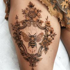 a woman's thigh with a bee and flowers tattoo on it