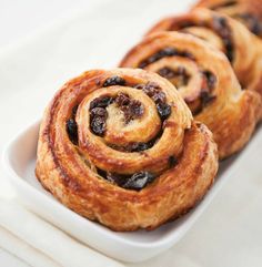 several cinnamon rolls on a white plate with some raisins in the middle,