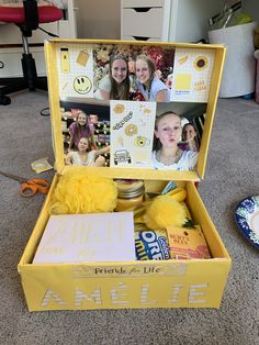 an open yellow box with pictures inside on the floor next to other items and decorations