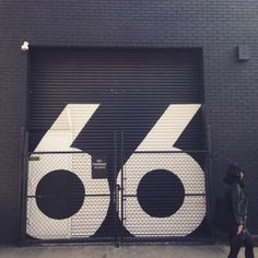 a woman walking past a closed garage door with the number sixty on it's side