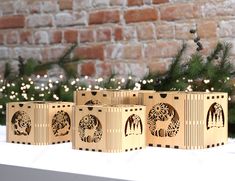 three wooden blocks with designs on them sitting in front of a christmas tree