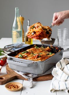 a person scooping food out of a casserole dish on top of a table