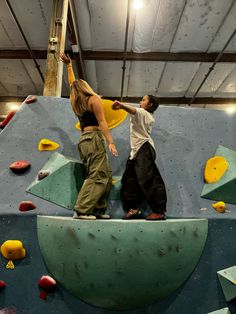 two people are climbing on a rock wall