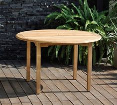 a wooden table sitting on top of a wooden floor next to a potted plant