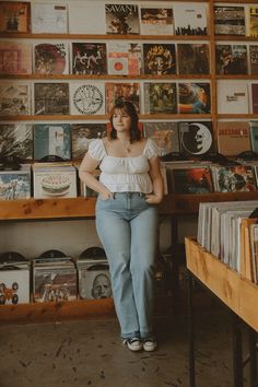 a woman standing in front of a record store with records on the wall behind her