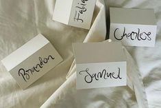 three pieces of paper with writing on them sitting on top of a white bed sheet