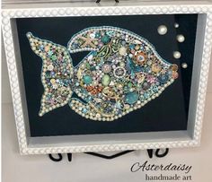 a fish made out of buttons and beads in a frame