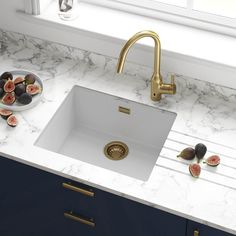 a white kitchen sink sitting under a window next to a bowl of figurines