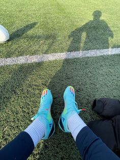 a person sitting on the ground with their feet up next to a soccer ball in front of them