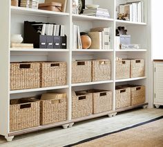 a white bookcase filled with lots of books and wicker baskets on top of it