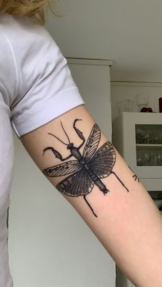 a woman's arm with a bug tattoo on the back of her left arm