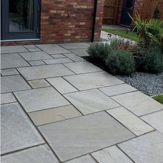 an outdoor patio with stone pavers and plants in the foreground, next to a brick building