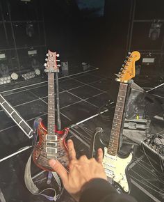 two guitars sitting on top of each other in front of a person's hand