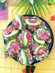 a blue plate topped with meat, avocado slices and red onion slaw