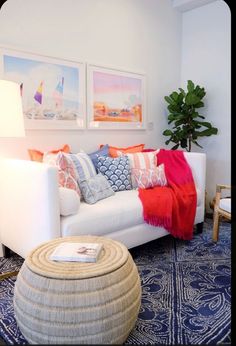 a living room with white couches and colorful pillows on the sofa, along with a blue rug