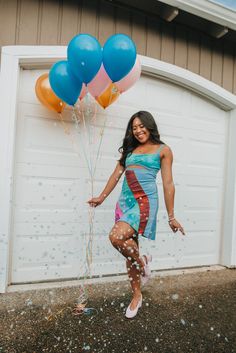 a woman is posing with balloons in front of a garage door and she has her arms out to the side