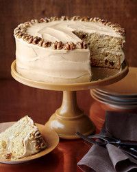 a cake with white frosting and pecans on top is sitting on a plate