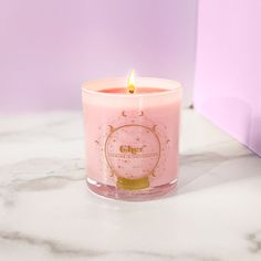 a pink candle sitting on top of a marble counter next to a box with the word cher written on it