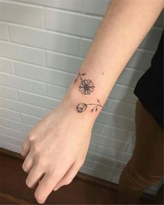 a woman's arm with a small flower tattoo on the left side of her wrist